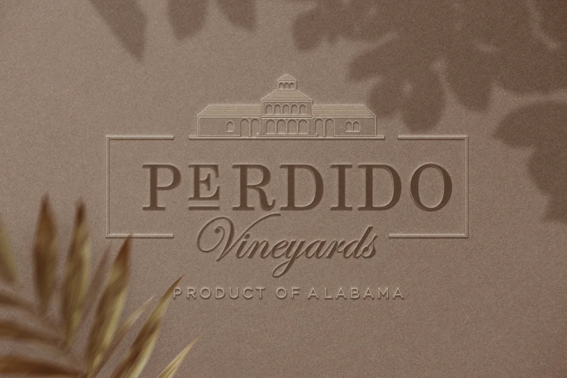 Aplicación del logo Perdido Vineyards en relieve sobre superficie marrón texturada con sombras vegetales